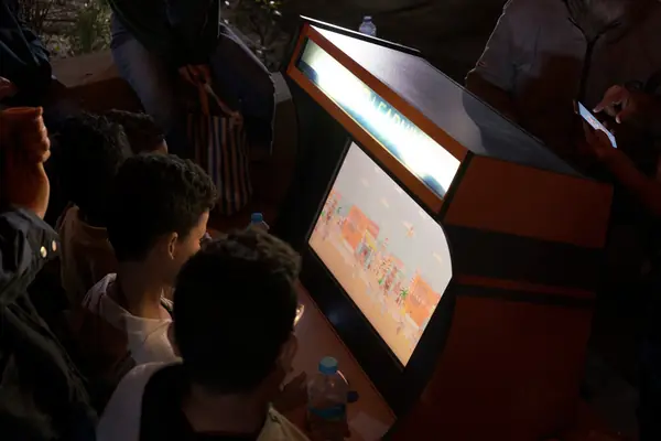Children playing Khef Teom on the arcade cabinet